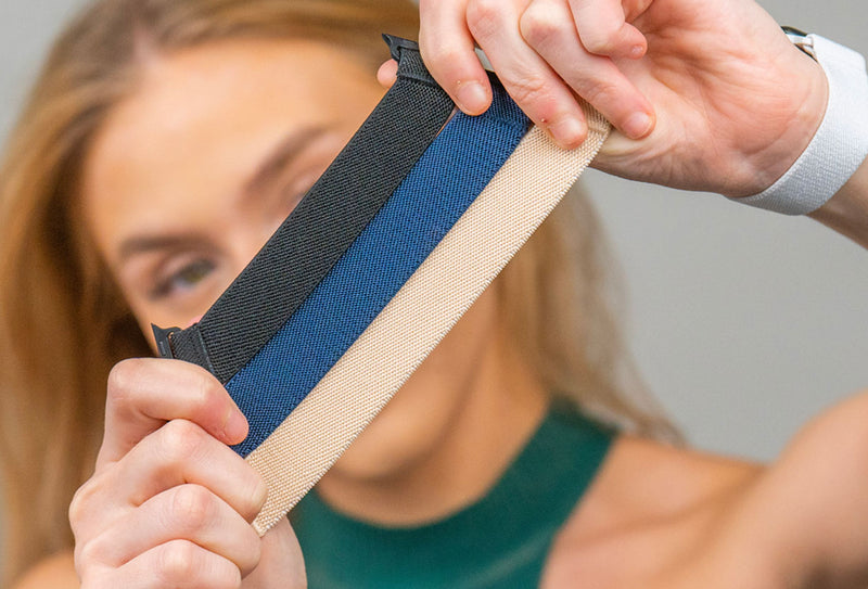 A women holding 3 nylon apple watch bands colored, black, sand, and blue